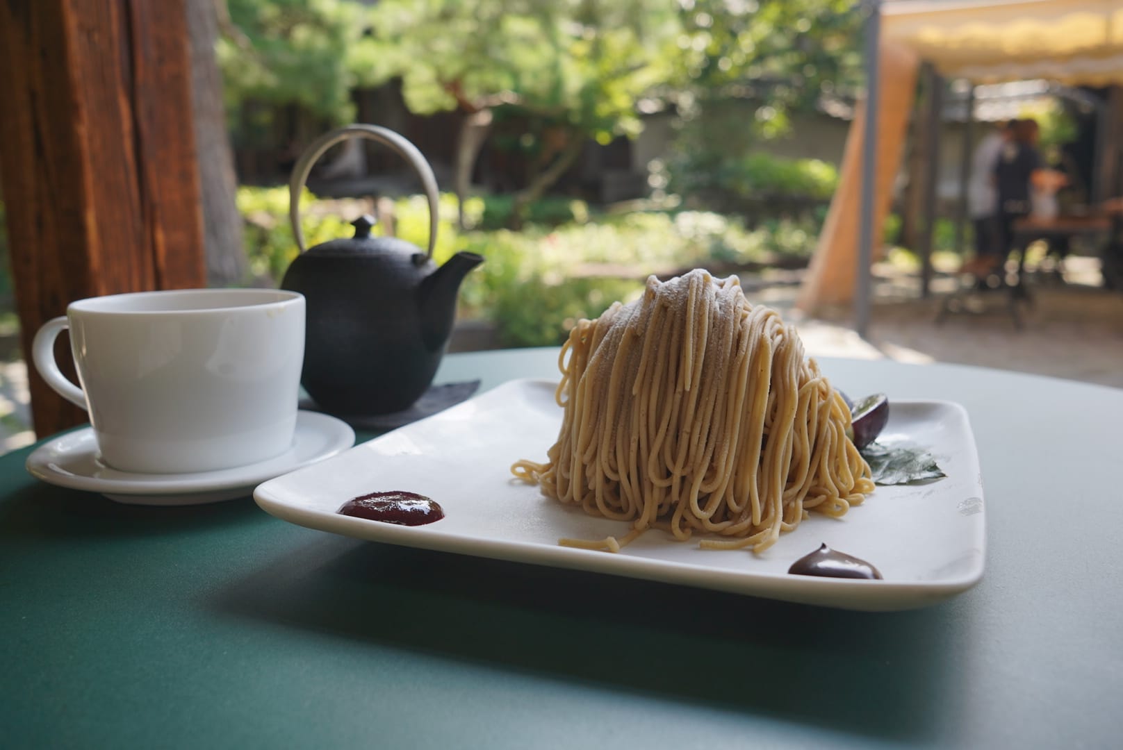 A diverse group of four people sit together at a table, happy as they enjoy a salad filled meal together.